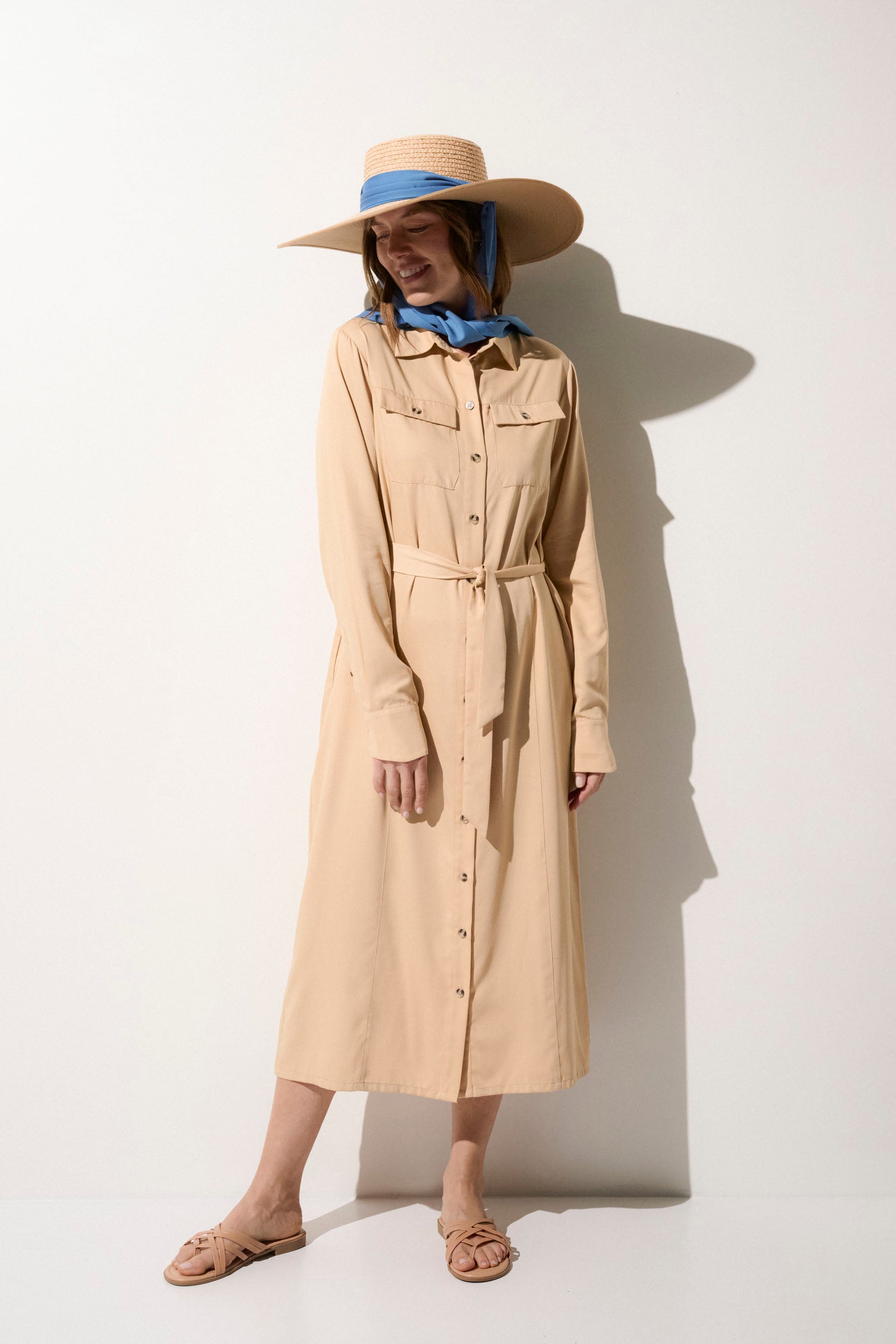 Femme portant une robe légère anti-UV beige, chapeau large UPF50+, idéale pour une journée ensoleillée.