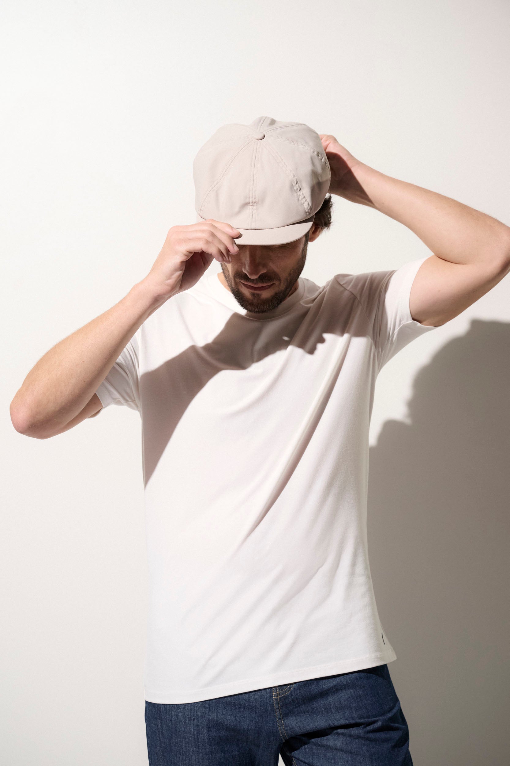 Homme portant une casquette gavroche anti-UV beige, avec un t-shirt léger, idéal pour la protection solaire quotidienne.