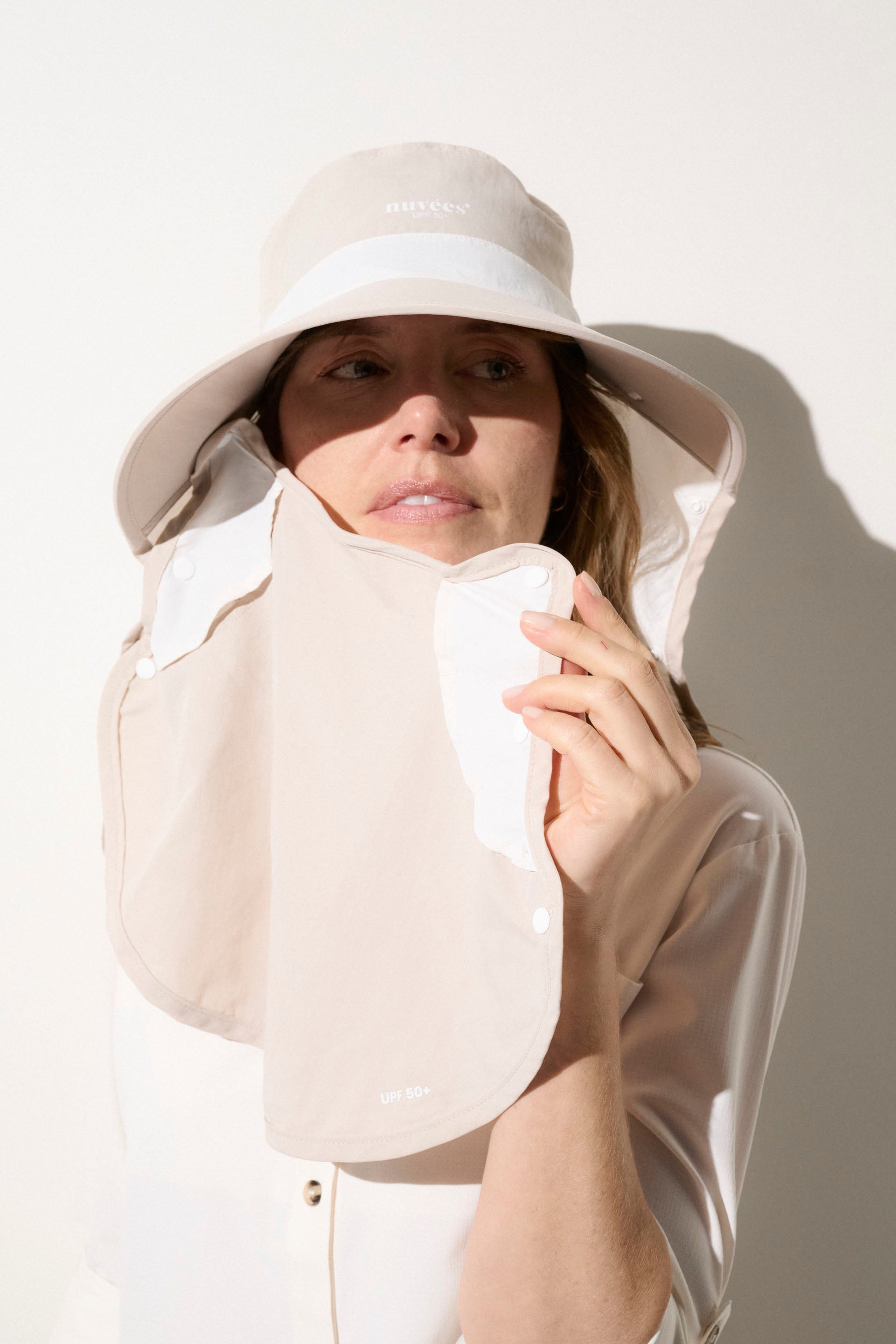 Femme portant un chapeau anti-UV beige UPF50+, offrant une protection solaire lors d'activités en plein air.