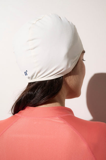 Bonnet de bain anti-UV blanc UPF50+ pour femme, idéal pour se protéger du soleil en piscine ou à la plage.