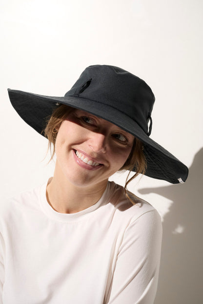 Chapeau anti-UV noir UPF50+ porté par une femme, idéal pour une protection solaire lors d'activités extérieures.